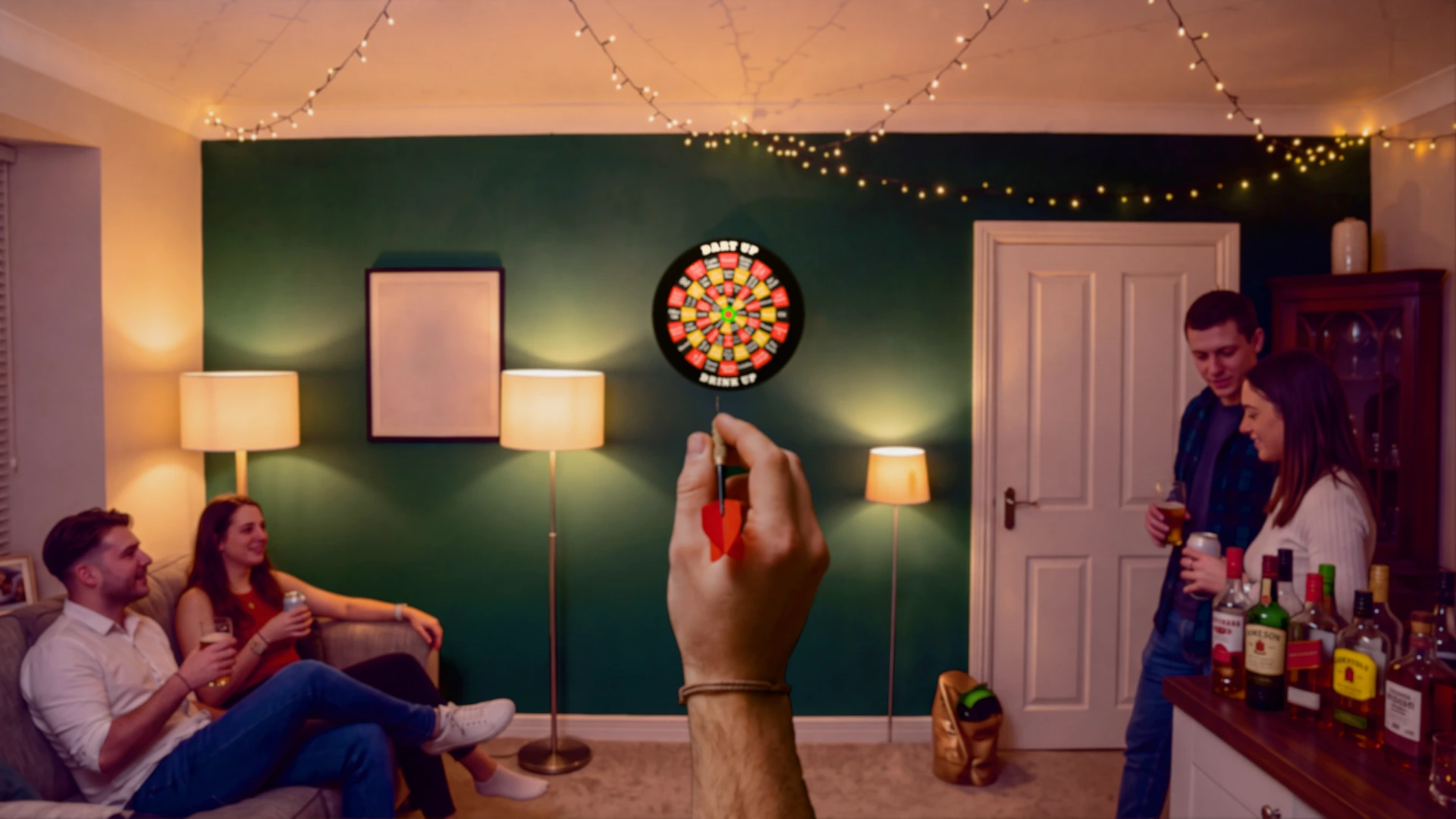 A hand aims a red dart at the DartUp party dartboard
